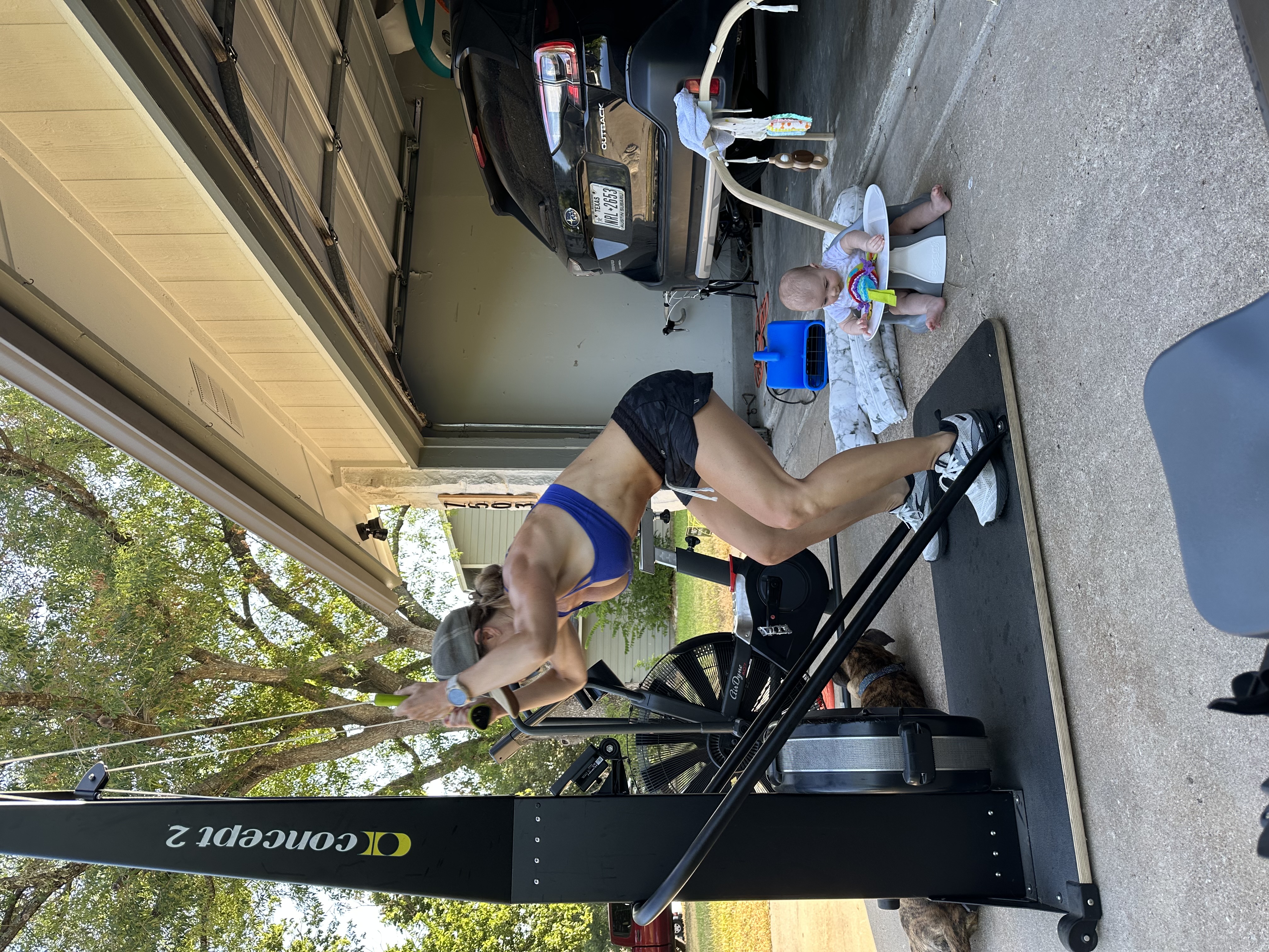 Mel training on the ski erg while her daughter plays nearby